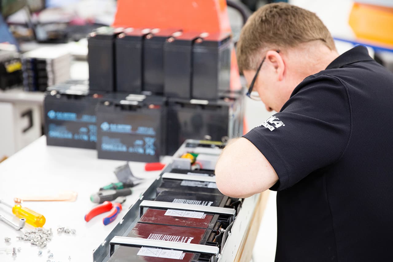 A Precision Electronics technician fitting replacement battery packs at the workbench