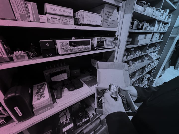 Technician selecting industrial electronic equipment from workshop shelves